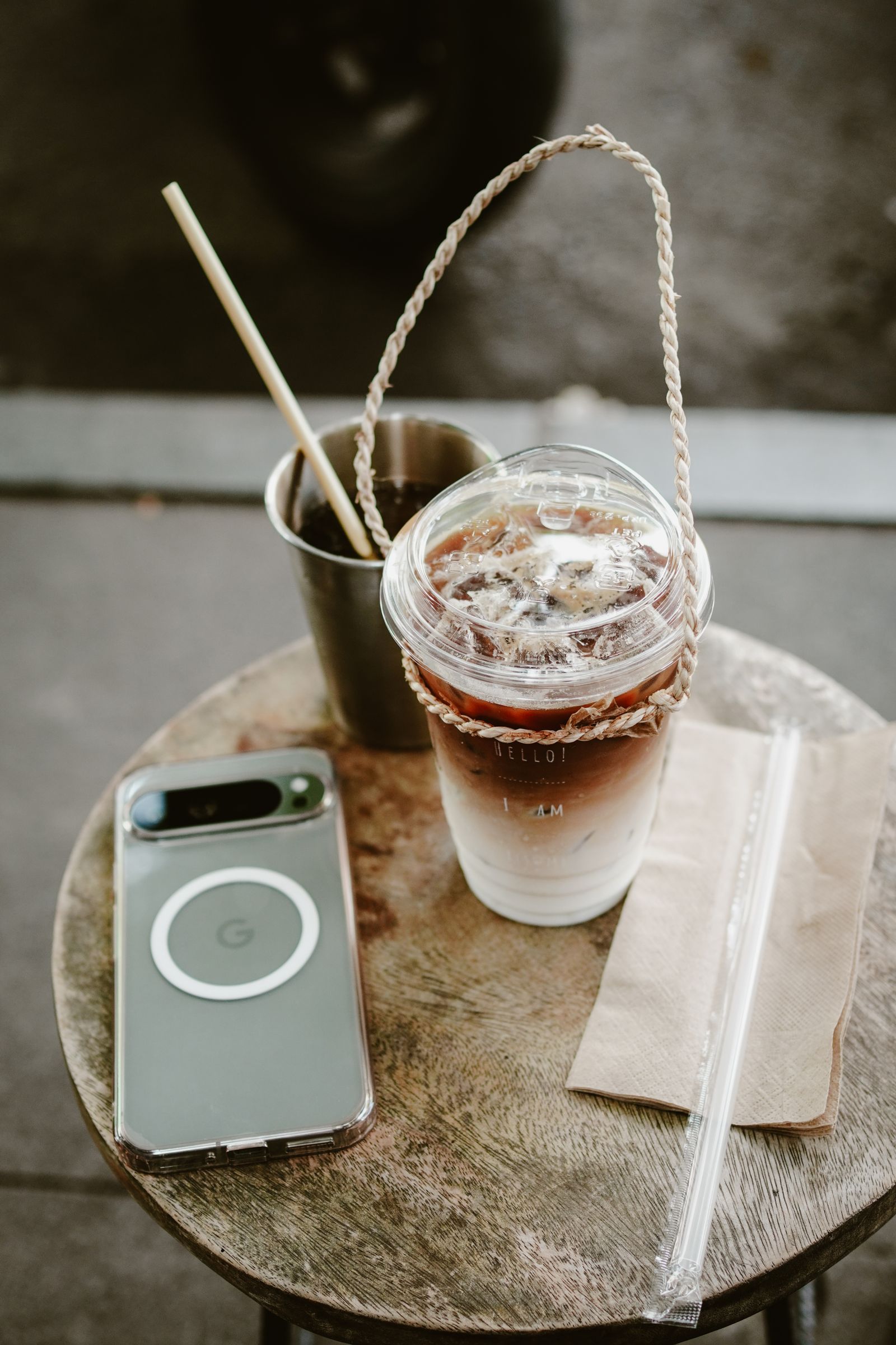 An iced coffee and a phone sitting together on a cafe table.